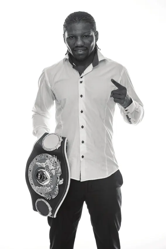 Hassan N'Dam en chemise blanche, ceinture de champion à la main